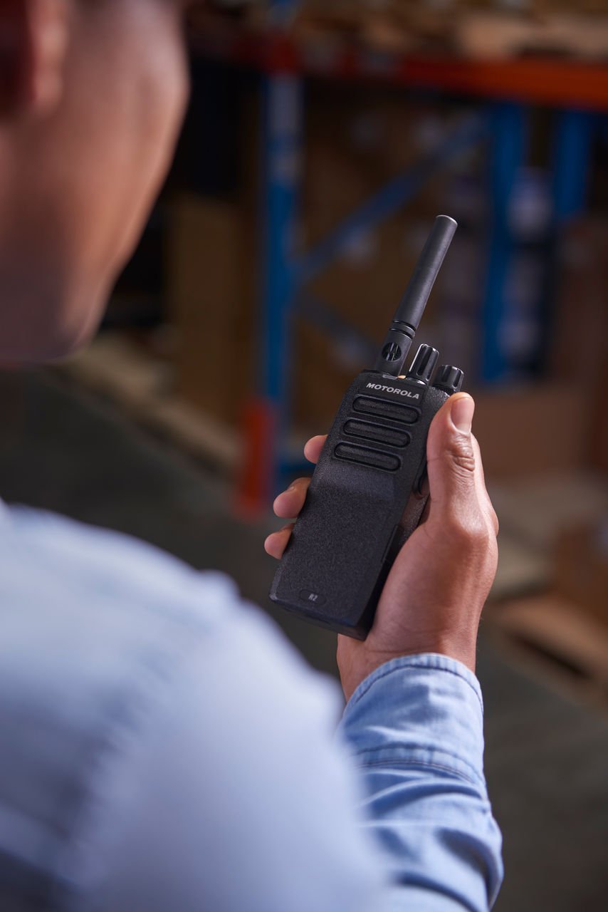 Profissional com rádio Motorola R2 em operação logística, cena de referência para locação de rádio comunicador